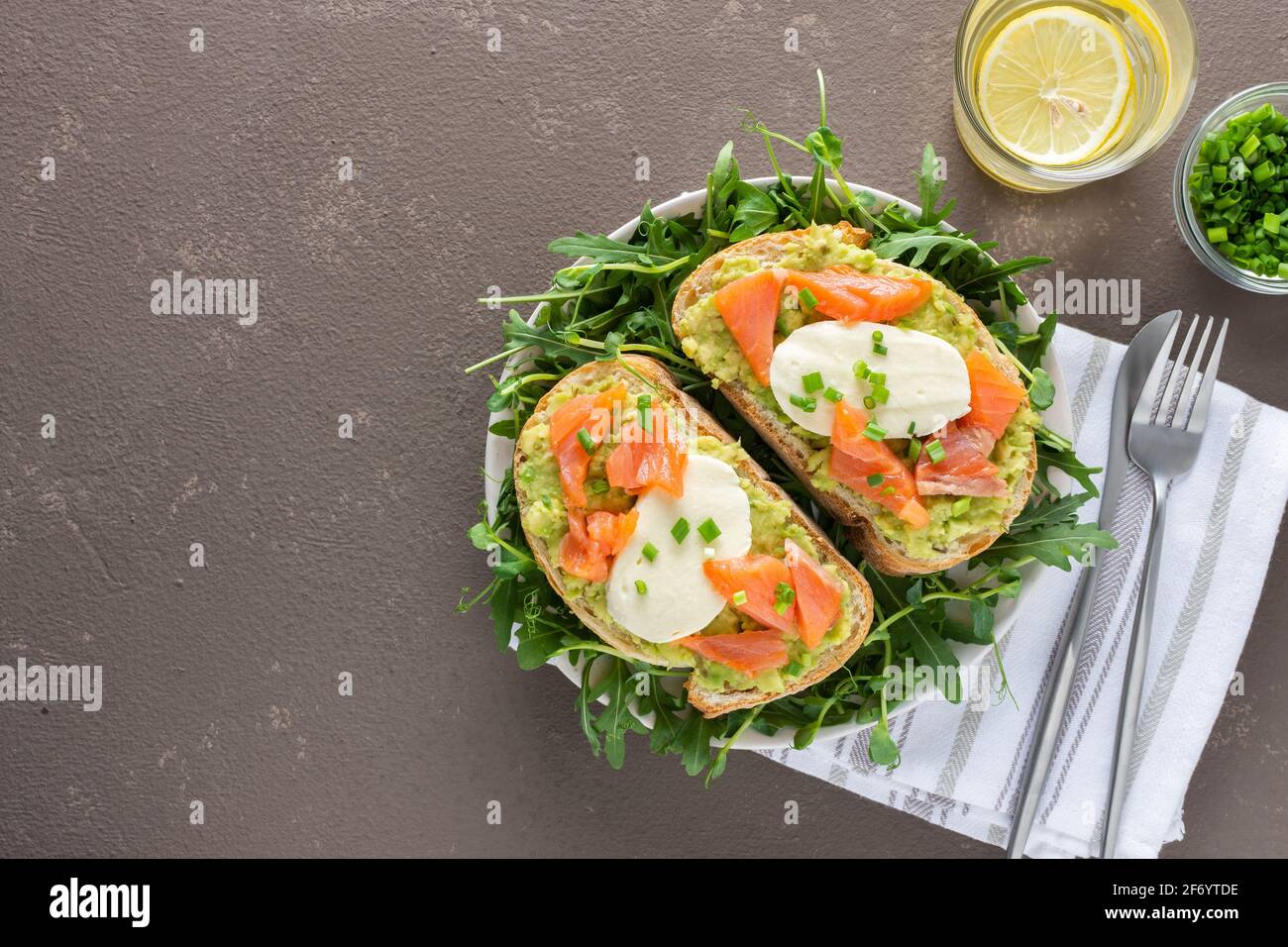 Leckeres herzhaftes Frühstück, Sandwiches mit Avocado-Paste, Lachs und Mozzarella auf einem Teller mit Rucola und Erbsensprossen Stockfoto