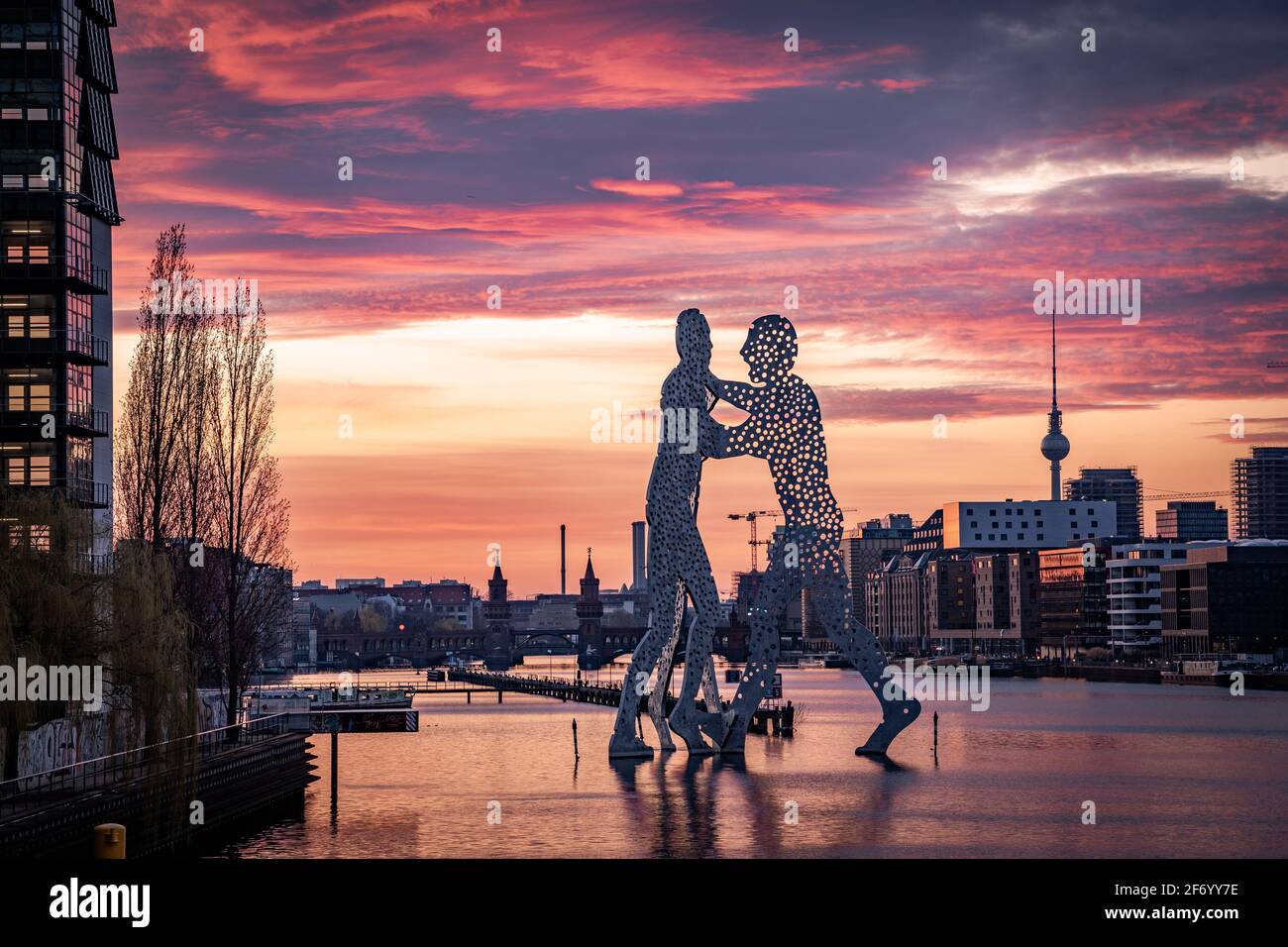 Statue von Molecule man im Flusslauf mit Aussicht Auf dem berliner fernsehturm und der oberbaumbrücke bei Sonnenuntergang Stockfoto