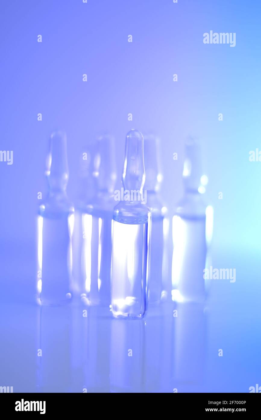 Medizin und Pharmakologie.Biotechnologie und Wissenschaft. Transparente Ampullen in blauen und violetten Tönen gesetzt.Ampullen mit Injektionslösung.Gesundheit und Stockfoto