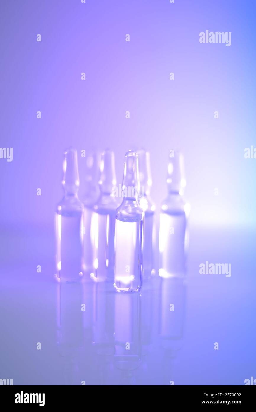 Medizin und Pharmakologie.Biotechnologie und Wissenschaft. Transparente Ampullen in hellblauen und violetten Tönen gesetzt.Ampullen mit Injektionslösung Stockfoto