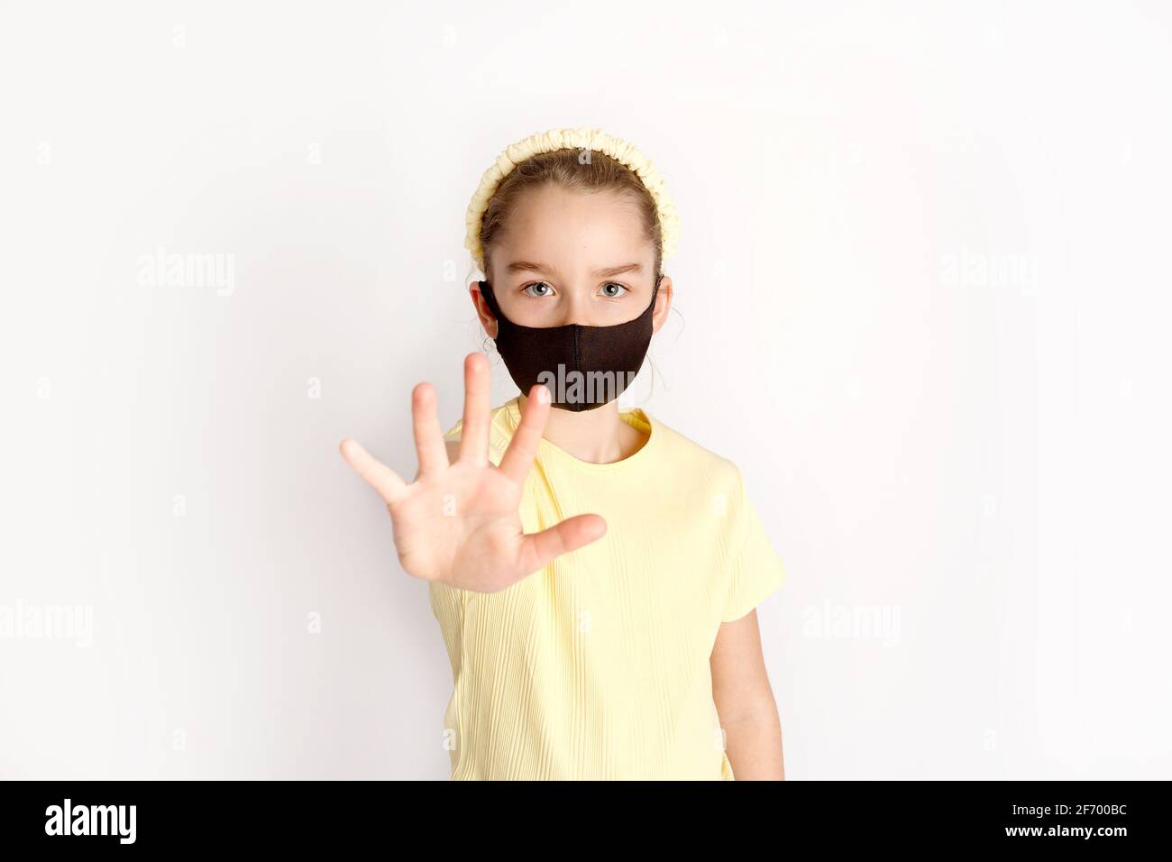 Ein Schulmädchen in einer schwarzen Schutzmaske lenkt die Aufmerksamkeit auf die Korrektheit und das obligatorische Tragen von Schutzmasken. Stockfoto