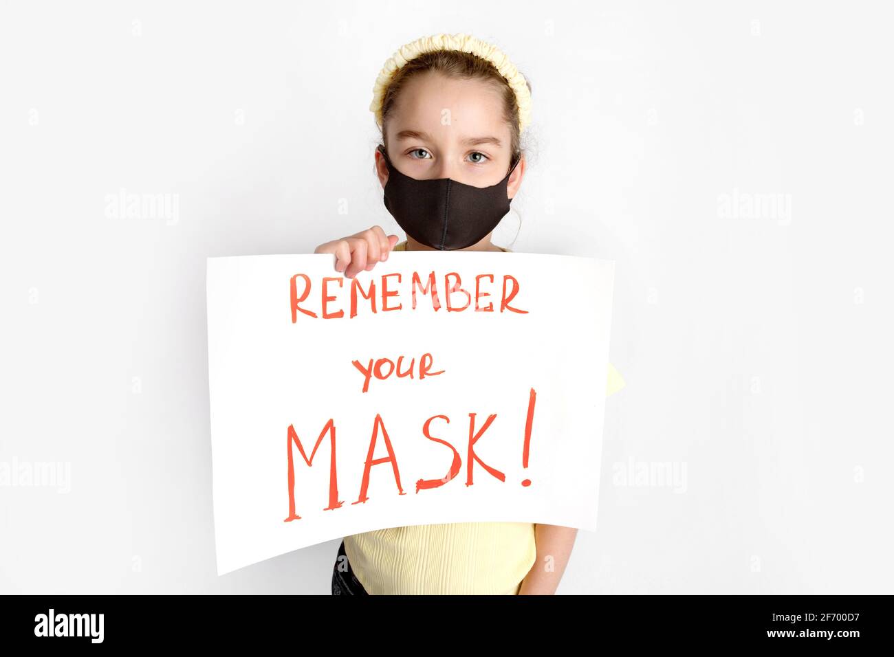 Ein Schulmädchen in einer schwarzen Schutzmaske lenkt die Aufmerksamkeit auf die Korrektheit und das obligatorische Tragen von Schutzmasken. Stockfoto