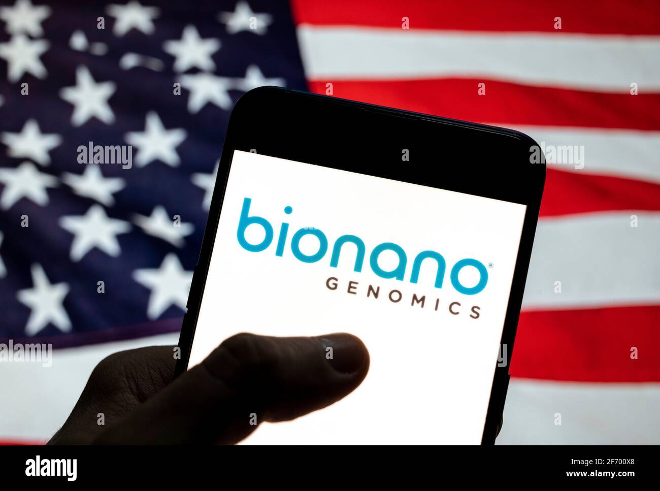 In dieser Abbildung die Plattform, um die langen Segmente der genomischen DNA-Biotechnologie-Unternehmen Bionano Genomics Logo auf einem Smartphone mit einer Flagge der Vereinigten Staaten im Hintergrund zu analysieren. Stockfoto