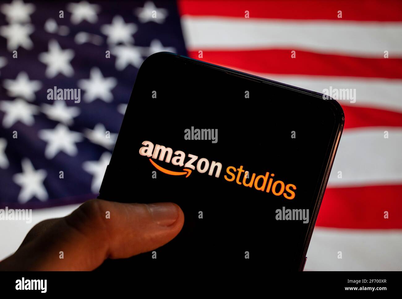 In dieser Fotolabbildung der amerikanische Fernsehproduktionshändler von Amazon, Amazon Studios Logo auf einem Smartphone mit einer Flagge der Vereinigten Staaten im Hintergrund zu sehen. Stockfoto