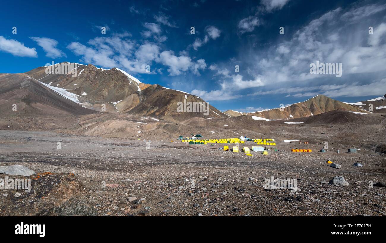 Achik Tash Basislager auf dem Lenin-Gipfel, dem Pamir-Gebirge, Kirgisistan, mit blauem Himmel und gelben Campingzelten Stockfoto