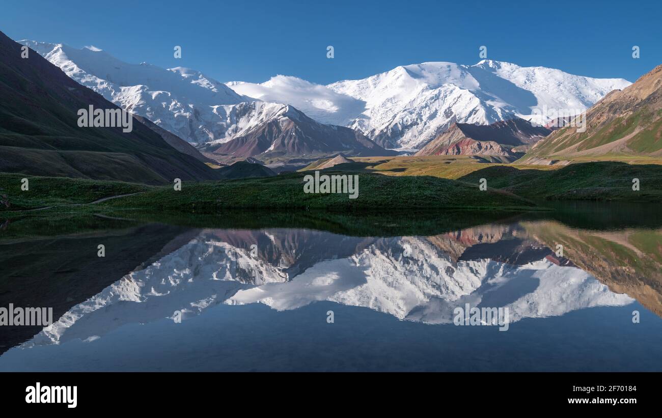 Ausgezeichnete Panoramasicht auf das Lenin Peak-Massiv vom Achik-Tash-Basislager mit Spiegelung in der ruhigen Gletscherlagune Kirgisistans Stockfoto