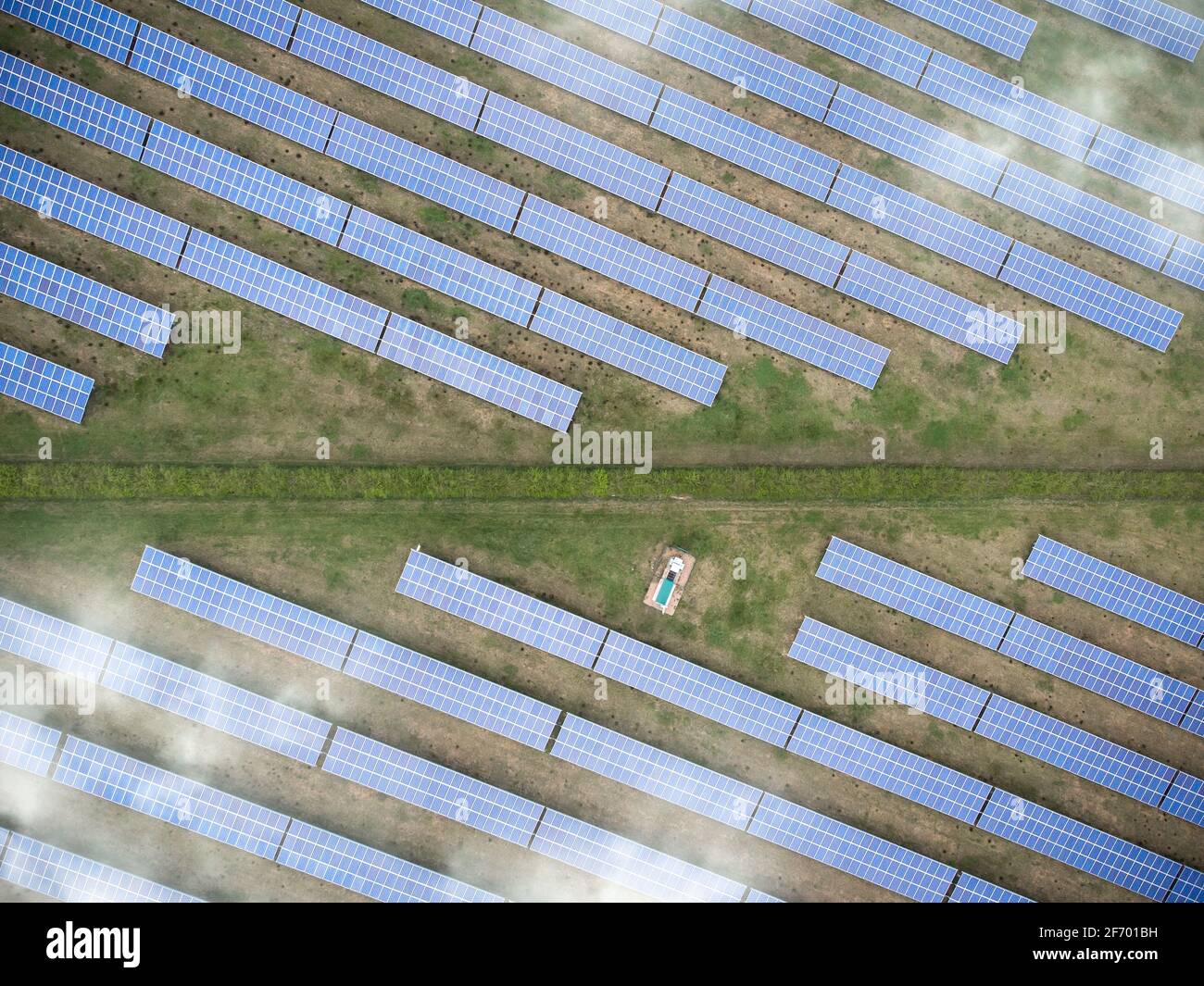 Sonne geht über Solarpanel-Farm in Reihen über sonnigem Feld auf. Erneuerbare grüne Stromerzeugung mit strahlendem Sonnenschein Luftaufnahme Drohne Stockfoto