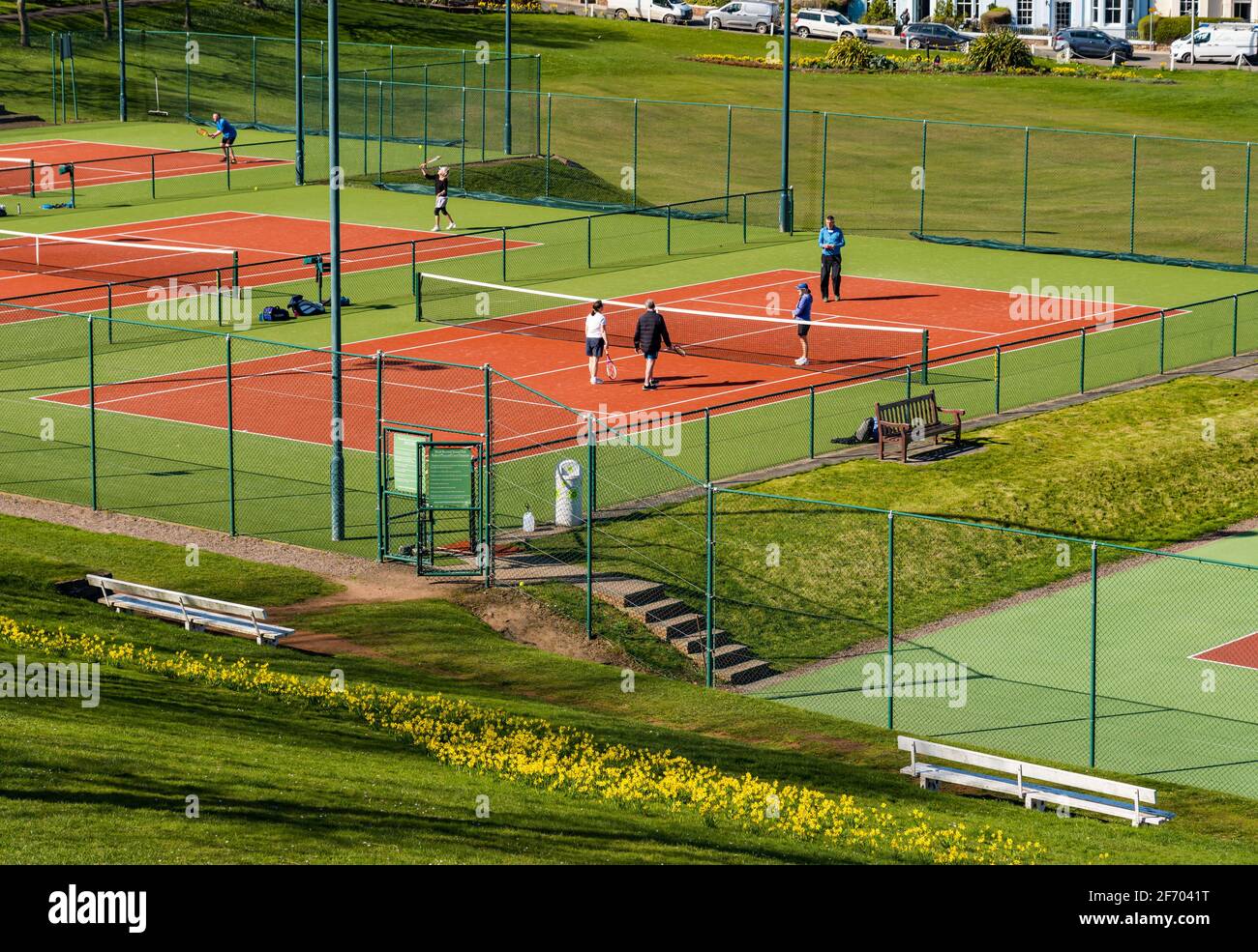 Tennisspieler auf öffentlichen Tennisplätzen im Park bei Sonnenschein, North Berwick, East Lothian, Schottland, Großbritannien Stockfoto