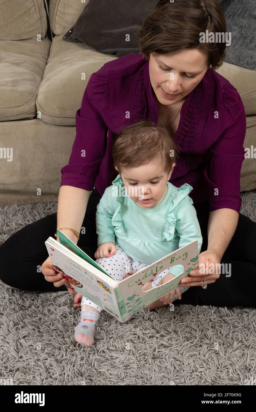 10 Monate altes Mädchen mit Mutter, vorlesen Stockfoto