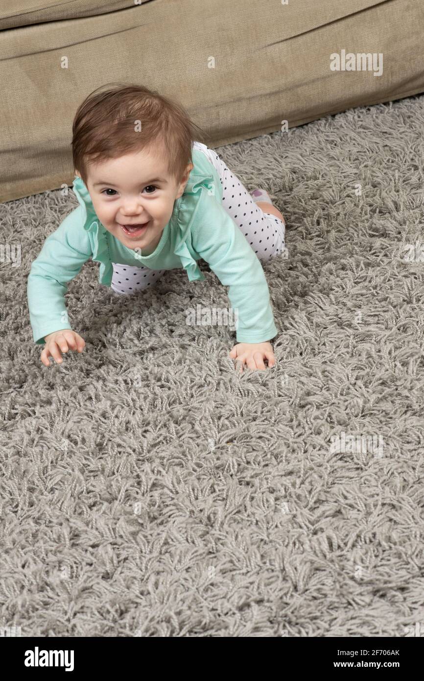 10 Monate altes Mädchen, das zu Hause auf dem Teppich kriecht Stockfoto