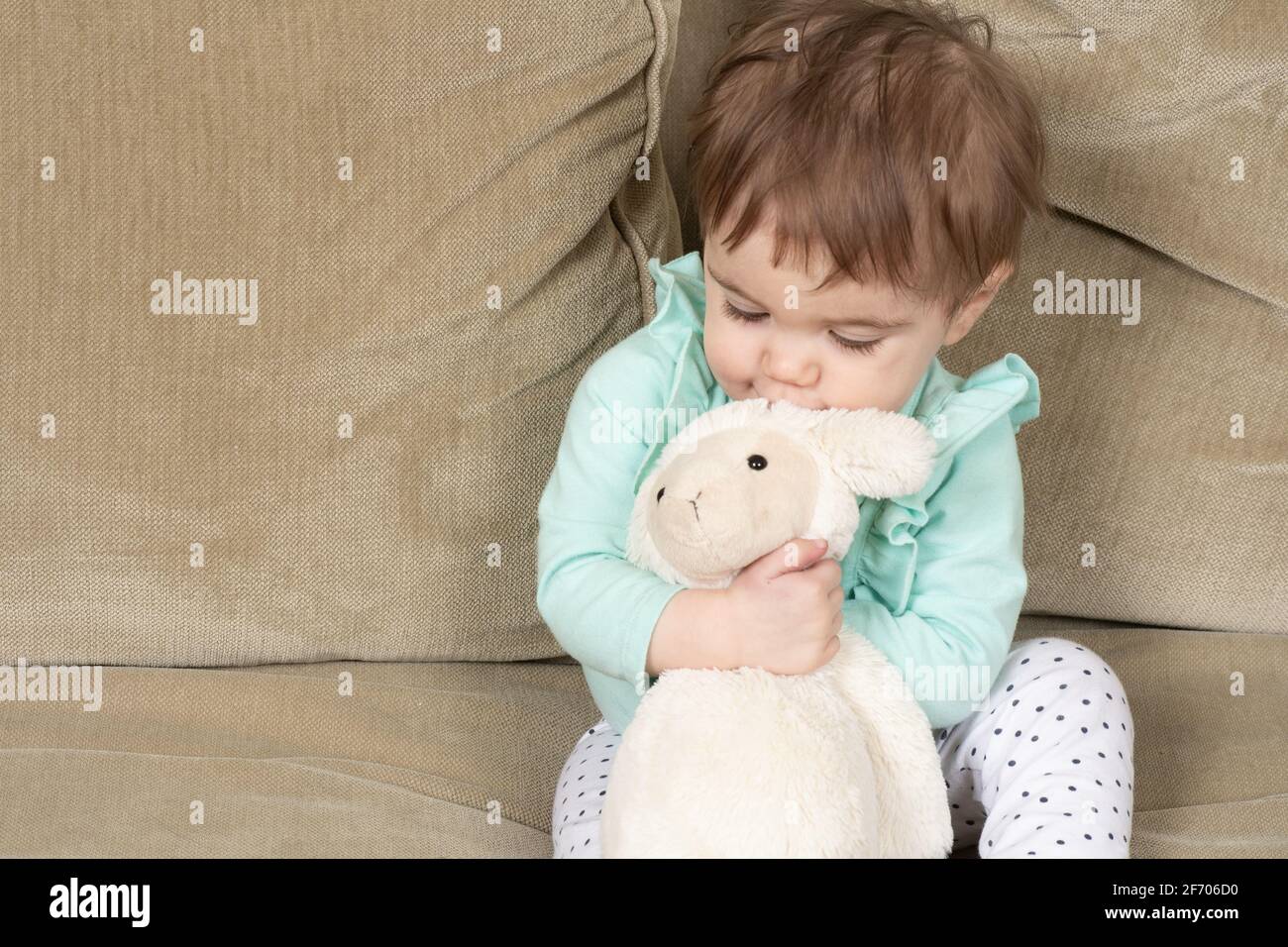 10 Monate altes Baby Mädchen umarmt Lieblings ausgestopftes Tier Lamm Spielzeug Stockfoto