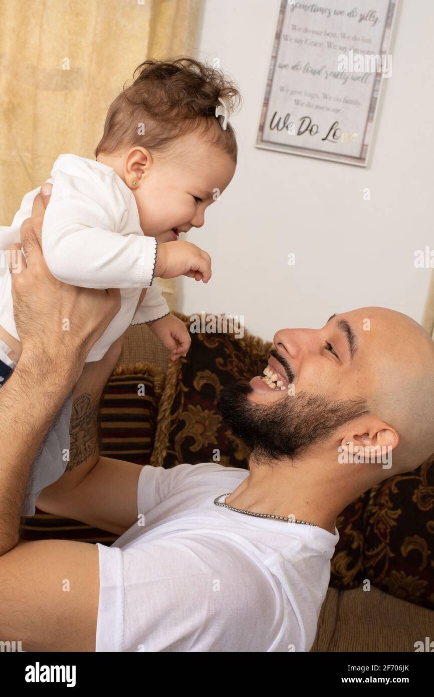 Das 7 Monate alte Mädchen, das mit dem Vater interagiert, hielt sich hoch Stockfoto