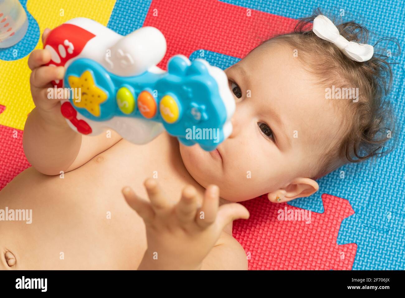 7 Monate altes Mädchen auf dem Rücken, Nahaufnahme, Spielzeug von einer Hand zur anderen bewegen Stockfoto