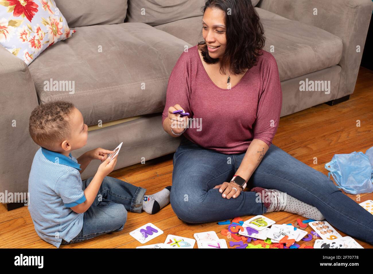 3-jähriger Junge mit seiner Mutter, spielt mit Alphabet- und Zahlenkarten, die ein Puzzleteil haben, das in das Kartenlernen zu Hause passt Stockfoto