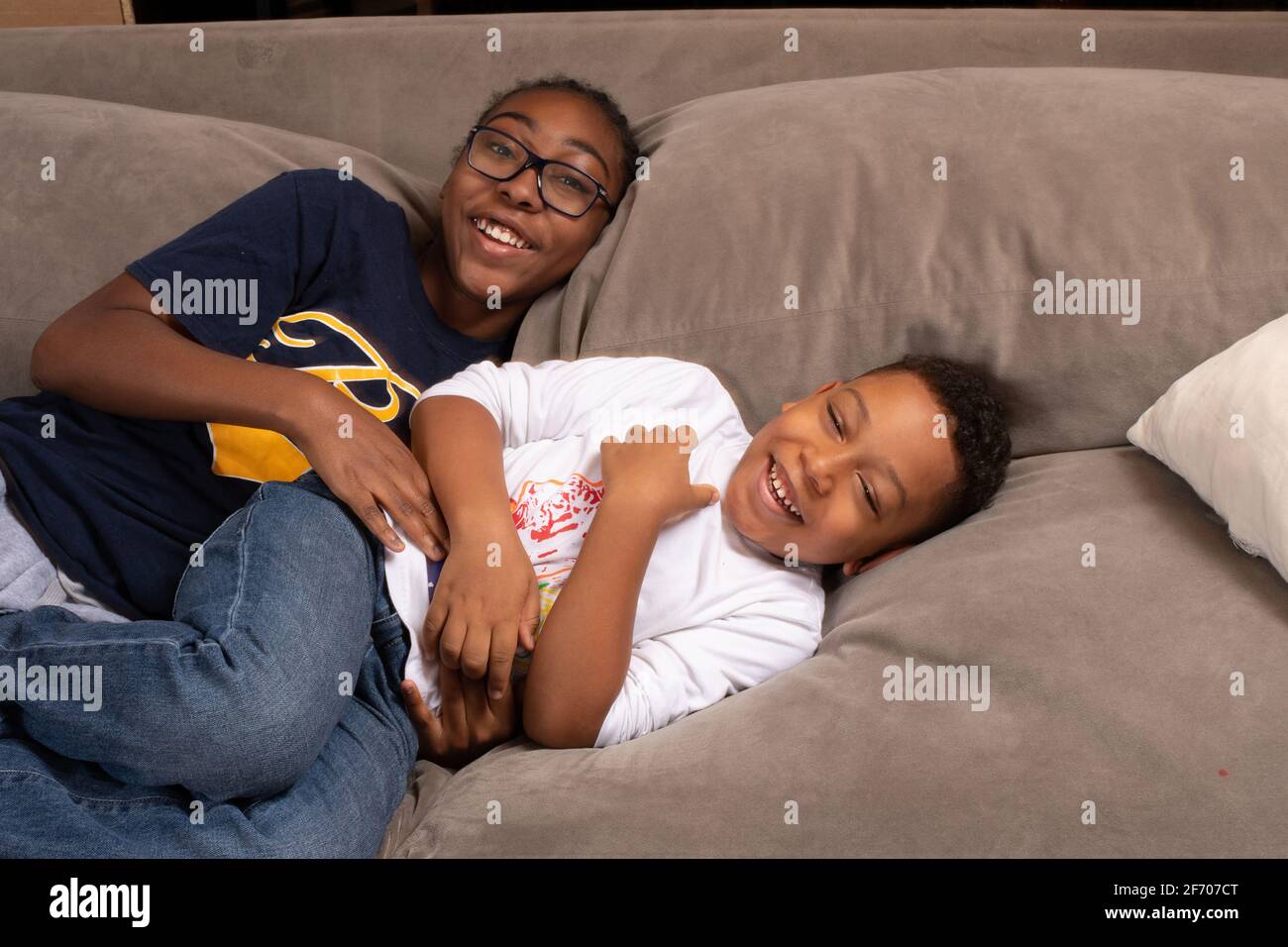 12-jähriges Mädchen mit ihrem 7-jährigen Bruder Fröhliches Porträt auf der Couch Stockfoto