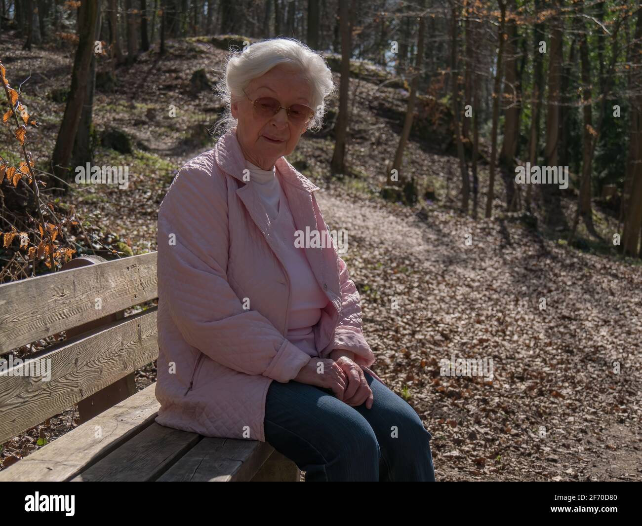 Ältere Frau, die allein auf der Parkbank sitzt Stockfoto