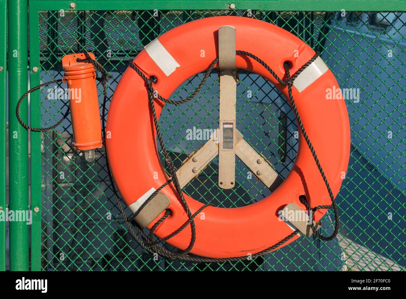 Unmarkierter Notfall oranger Rettungsring auf einem Handelsboot gegen Ein grüner Hintergrund Stockfoto