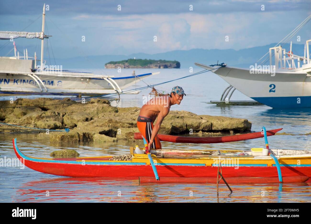 Philippinischer Fischer lächelt, als er sich darauf vorbereitet, sein Auslegerkanu zu nehmen, um in der Visayan Sea vor Moalboal, Cebu Island, Philippinen, zu fischen. Stockfoto