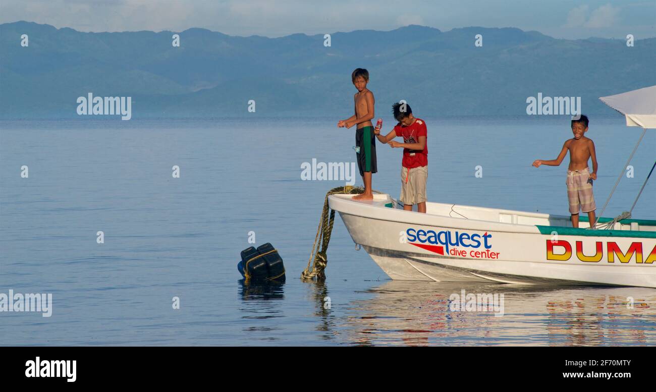 Philippinische Kinder fischen mit einer Schnur vor einem Boot in der Visayan Sea direkt vor Moalboal, Cebu Island, Philippinen. Negros Island Beyond, Central Visayas Region. Stockfoto