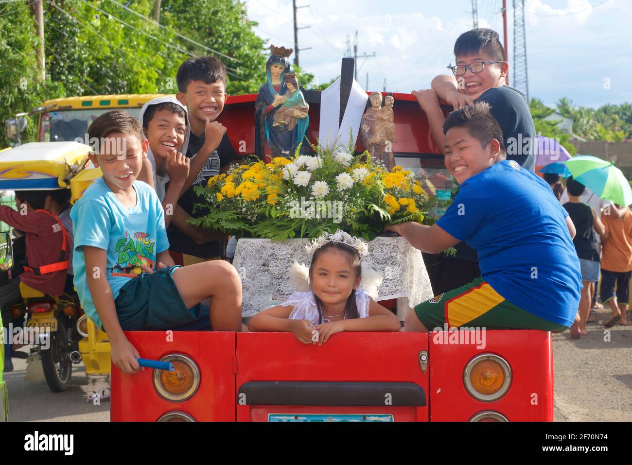 Schweben Sie auf der Rückseite eines Pickups mit Kindern und Heiligenbildern zu den Maifeierlichkeiten von Flores de Mayo... die Kinder bieten Blumen vor dem Bild der Jungfrau Maria als Symbol der Liebe, Zuneigung und Verehrung an. In Der Nähe Von Toledo City, Central Visayas, Cebu, Philippinen. Stockfoto