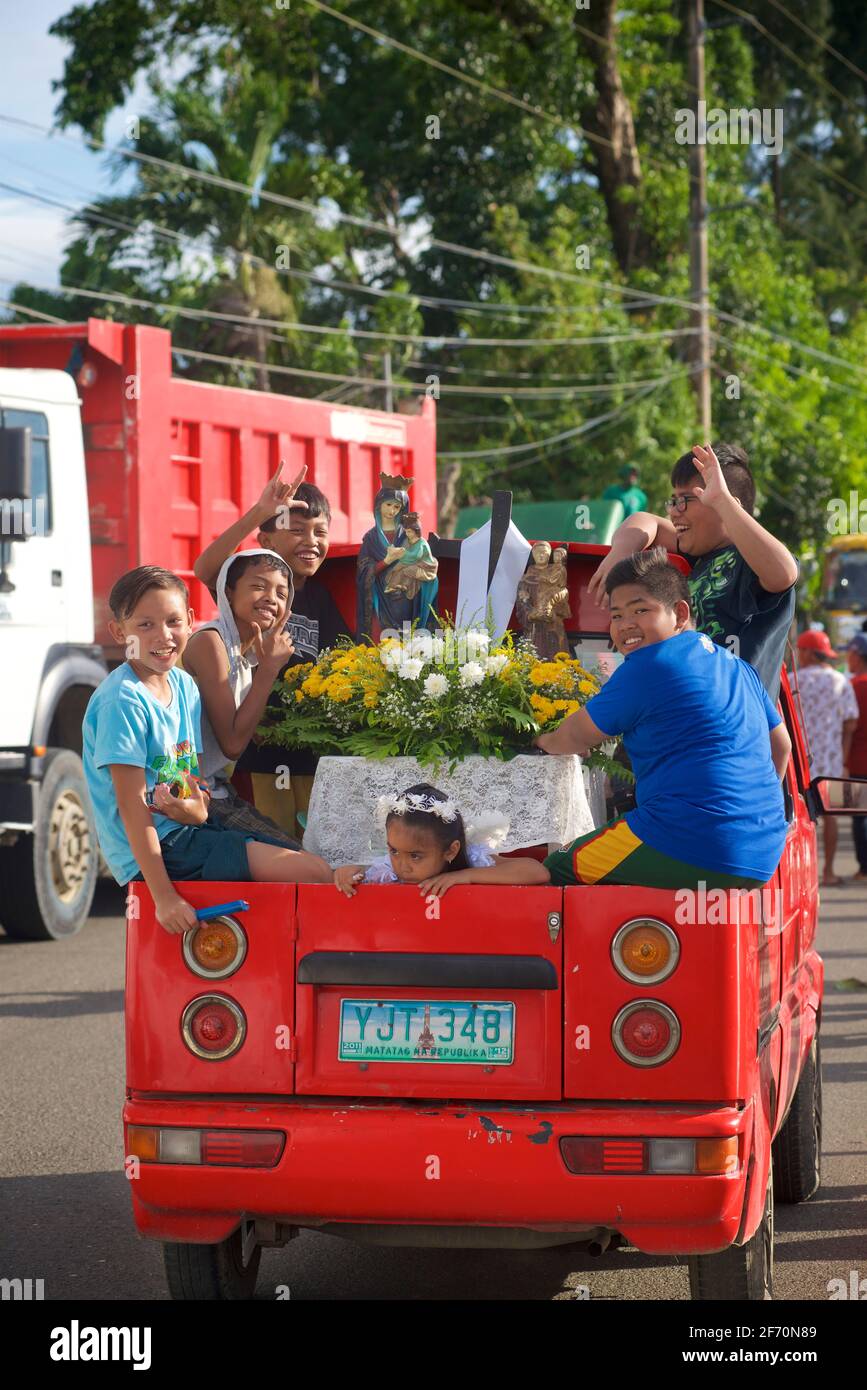 Schweben Sie auf der Rückseite eines Pickups mit Kindern und Heiligenbildern zu den Maifeierlichkeiten von Flores de Mayo... die Kinder bieten Blumen vor dem Bild der Jungfrau Maria als Symbol der Liebe, Zuneigung und Verehrung an. In Der Nähe Von Toledo City, Central Visayas, Cebu, Philippinen. Stockfoto