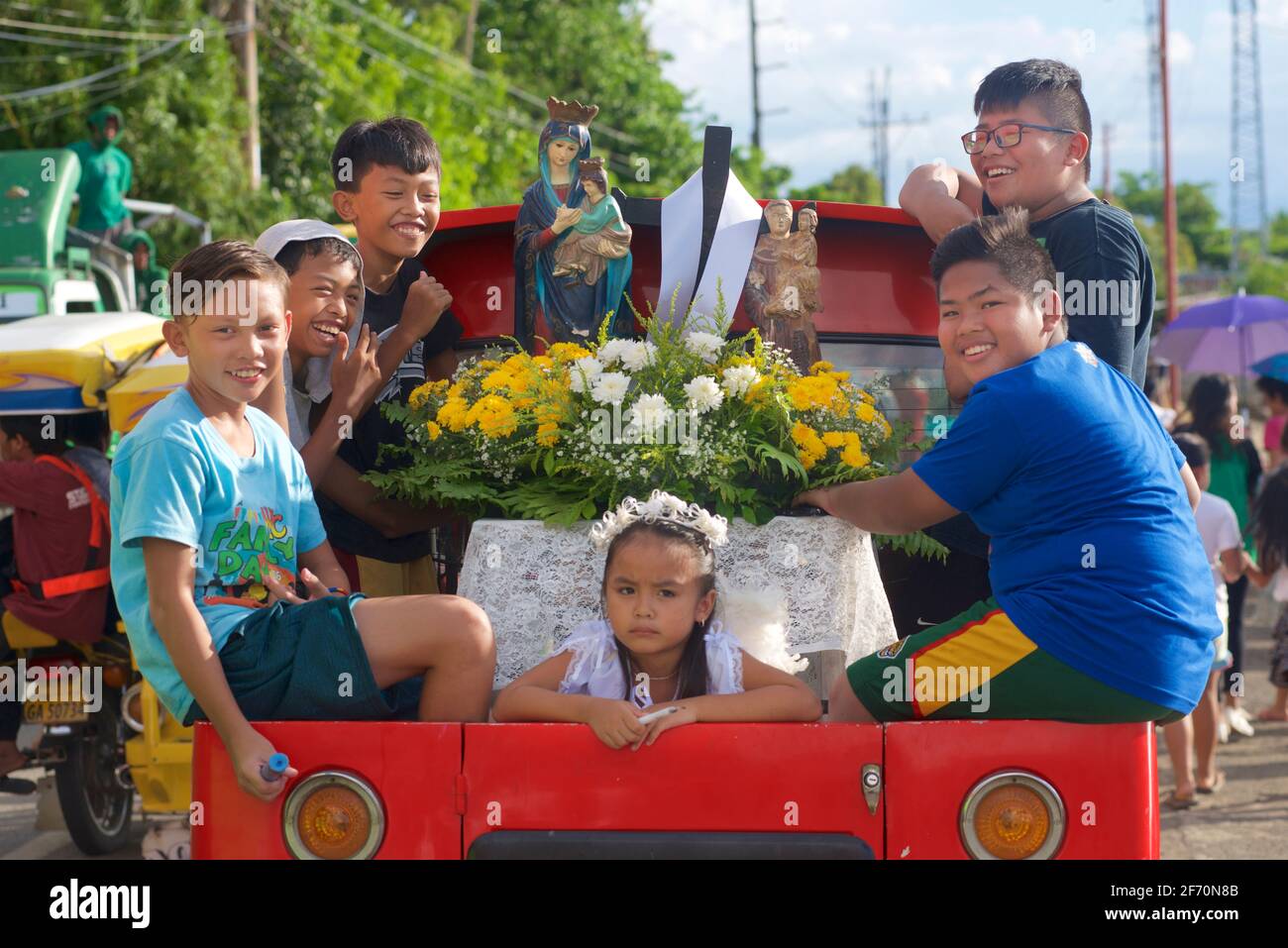 Schweben Sie auf der Rückseite eines Pickups mit Kindern und Heiligenbildern zu den Maifeierlichkeiten von Flores de Mayo... die Kinder bieten Blumen vor dem Bild der Jungfrau Maria als Symbol der Liebe, Zuneigung und Verehrung an. In Der Nähe Von Toledo City, Central Visayas, Cebu, Philippinen. Stockfoto