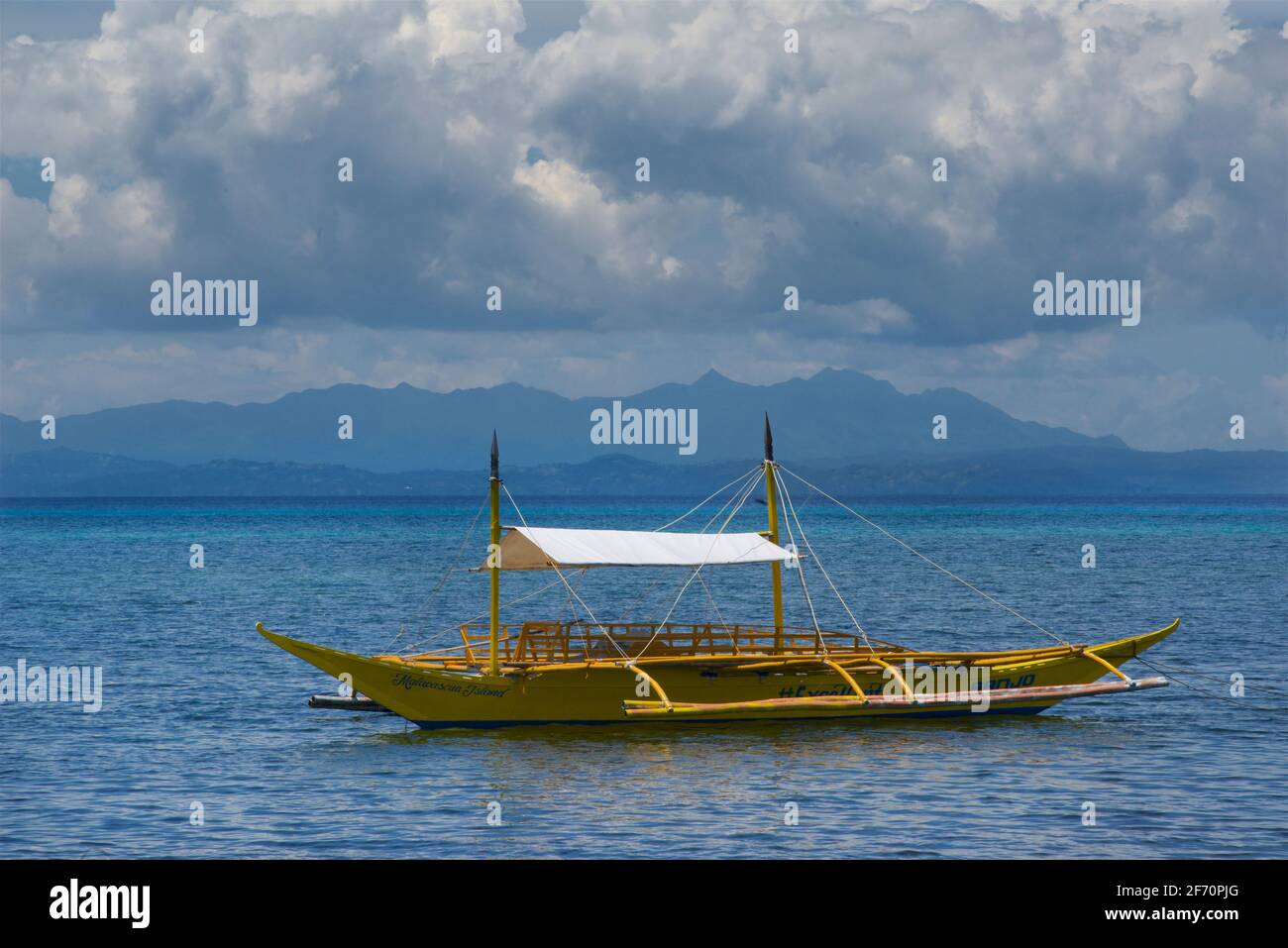 Ein gelbes Auslegerkanu, das vor der Küste in der Visayansee festgemacht ist. Malapascua Island, Cebu, Philippinen. Stockfoto