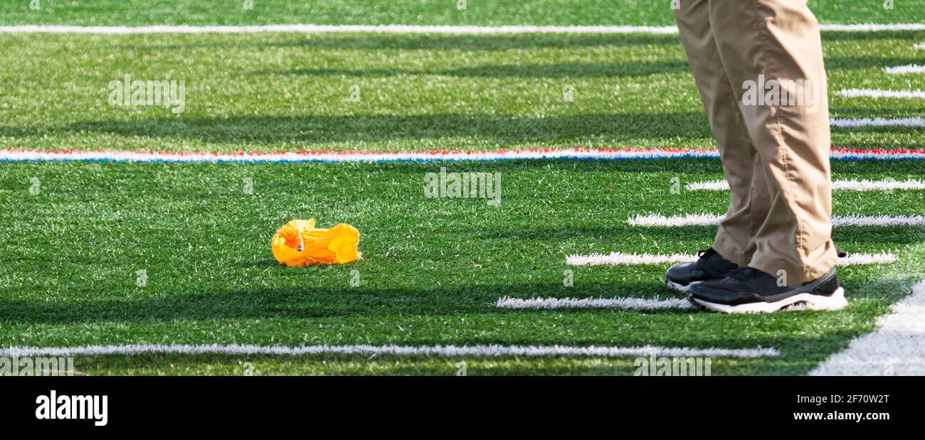 Fußballoffizier wirft die gelbe Flagge auf den Boden vor den Füßen der Hachentrainer. Stockfoto