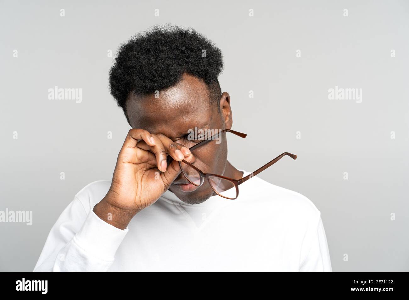 Erschöpfter schwarzer Mann zieht die Brille ab, die seine Augen reibt fühlt sich nach der Arbeit am Laptop müde. Überlastung. Stockfoto