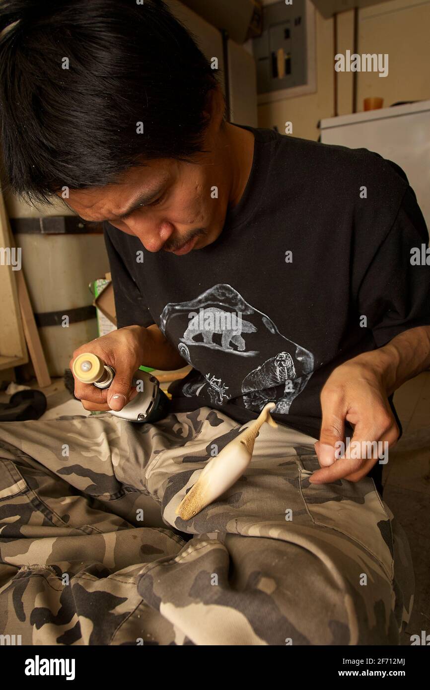 Der in Pond Inlet lebende Inuit-Künstler kreiert zwei Narwhale aus cariboo-Knochen. Stockfoto