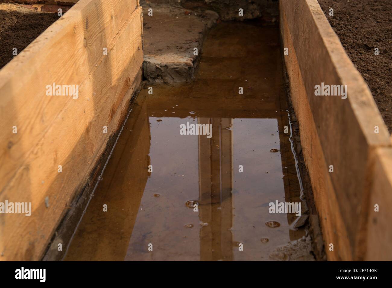 Schmelzwasser überschwemmten Weg zwischen den Betten im Gewächshaus. Stockfoto