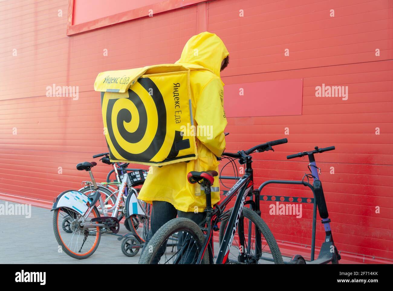 Krasnodar, Russland - 2 2021. April: Yandex-Kurierlieferer von Eat während der Quarantäne steht in der Nähe des Fahrrads Stockfoto