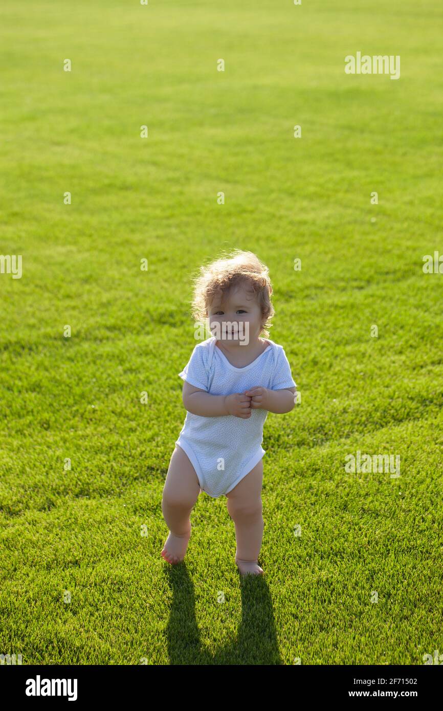 Fröhliches Baby im Gras auf dem Fieald am Sommerabend. Lächelndes Kind im Freien. Stockfoto