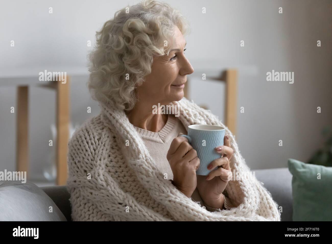 Glückliche nachdenkliche ältere Dame in Schal gewickelt Stockfoto