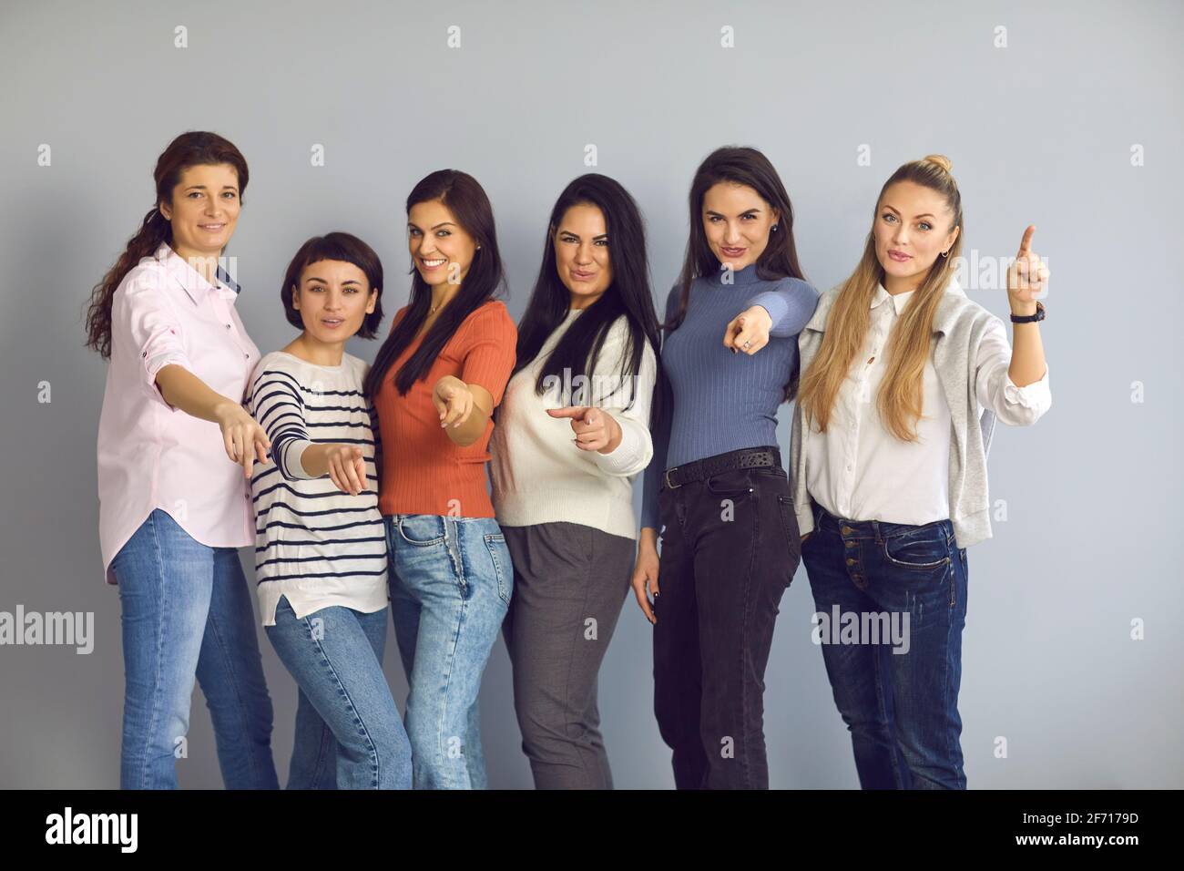 Eine Gruppe glücklicher Frauen, die mit den Fingern auf die Kamera zeigen und Sie einladen, sich ihrem Team anzuschließen Stockfoto