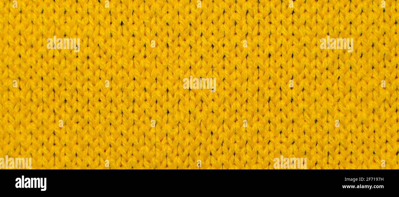 Gelber Synthetik-Strickstoff aus nächster Nähe. Gestrickter Stoff Textur Hintergrund Stockfoto