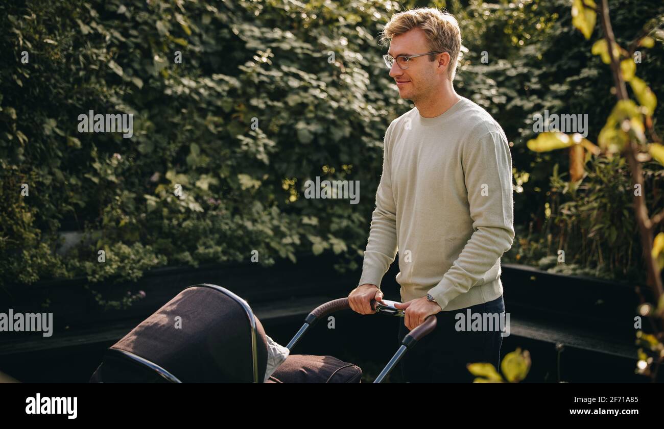 Mann auf Vaterschaft verlassen schießender Kinderwagen. Vater mit Baby im Kinderwagen im Freien. Stockfoto