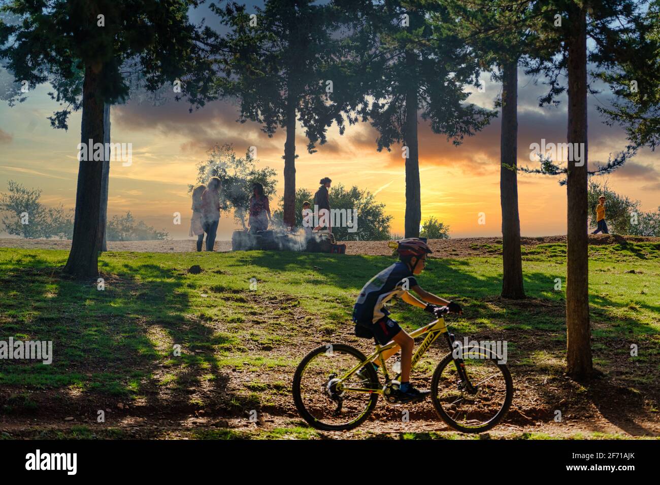 GRANADA, ANDALUSIEN, SPANIEN. NOVEMBER 2020. Menschen, die im Wald grillen, während ein junger Radfahrer bei Sonnenuntergang Sport macht. Stockfoto