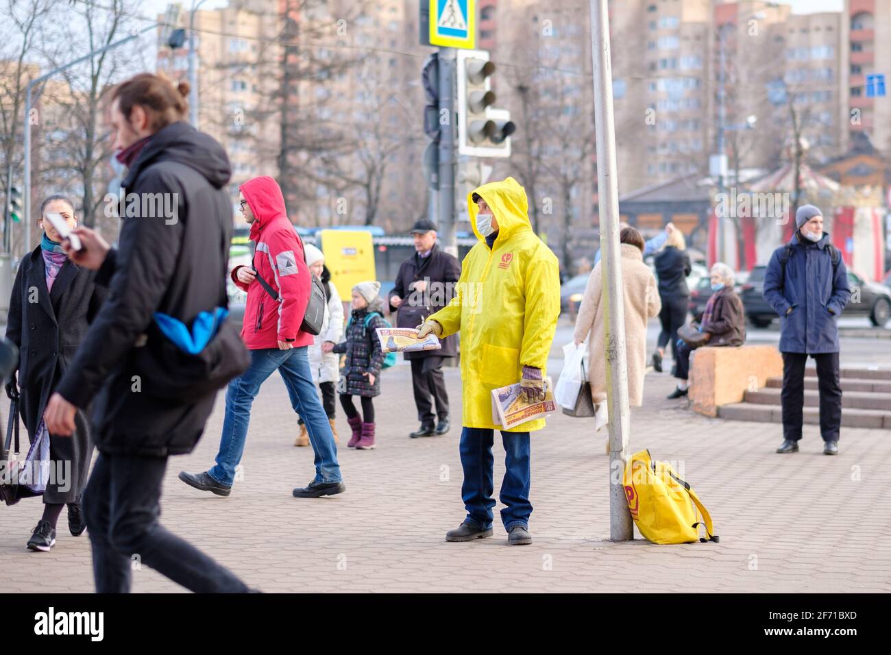 Moskau. Russland. März 26, 2021. Ein Mann in einem gelben Regenmantel und einer medizinischen Maske verteilt politische Propagandazeitungen an die Passanten Stockfoto