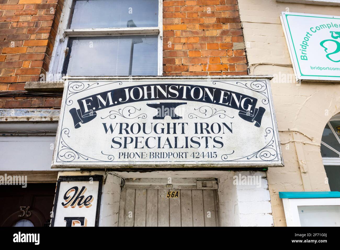 Gemaltes Namensschild von F M Johnston, eng, schmiedeeisernen Spcialisten, über einer Tür in der South Street, Bridport, einer Marktstadt in Dorset, Südwestengland Stockfoto