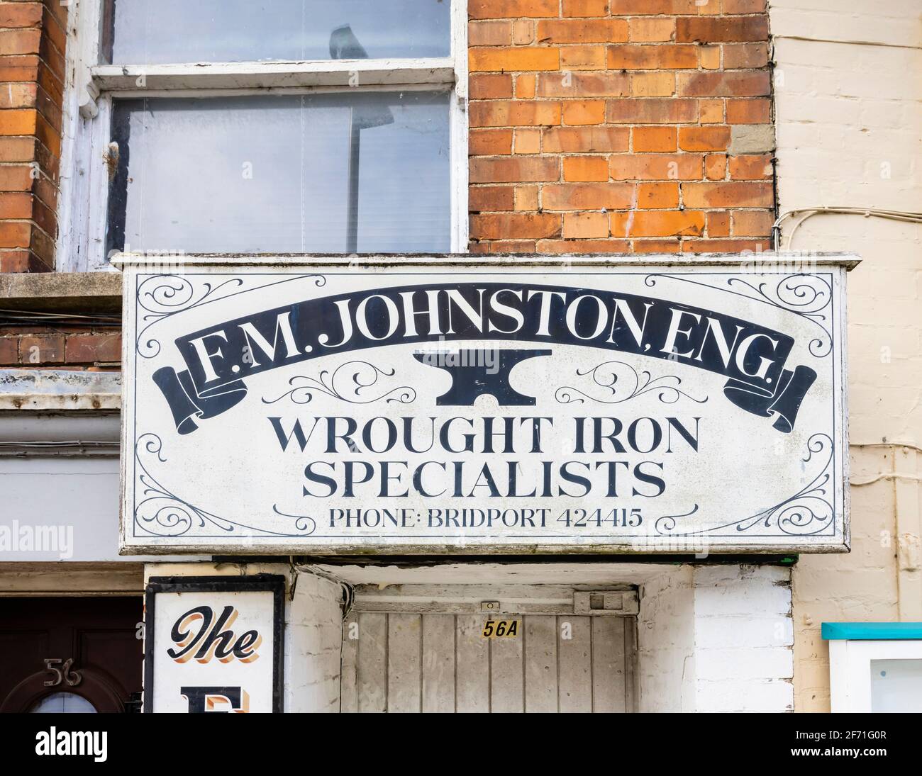 Gemaltes Namensschild von F M Johnston, eng, schmiedeeisernen Spcialisten, über einer Tür in der South Street, Bridport, einer Marktstadt in Dorset, Südwestengland Stockfoto