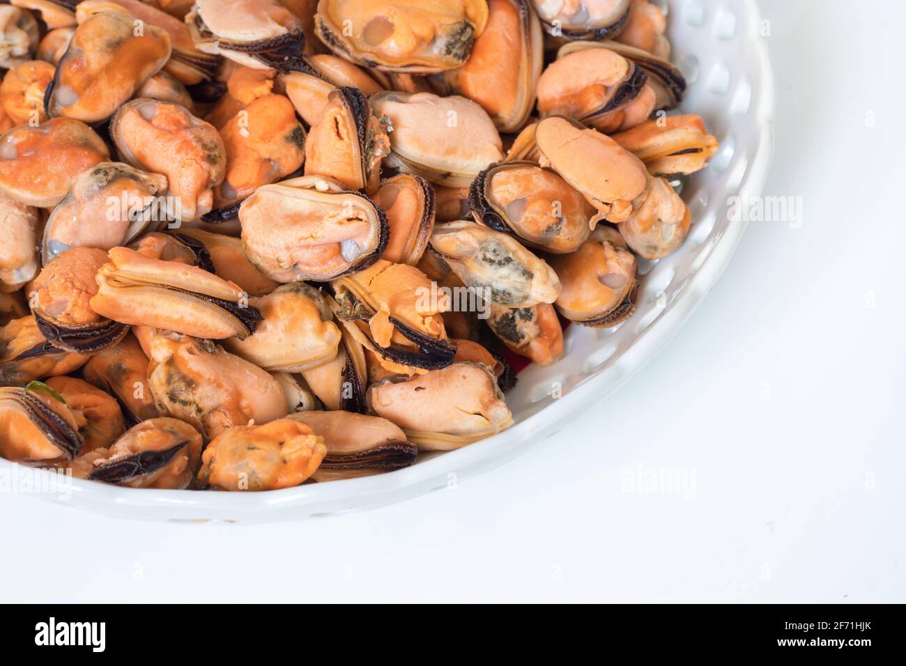 Gekochte Muscheln auf einem Teller auf weißem Hintergrund. Stockfoto