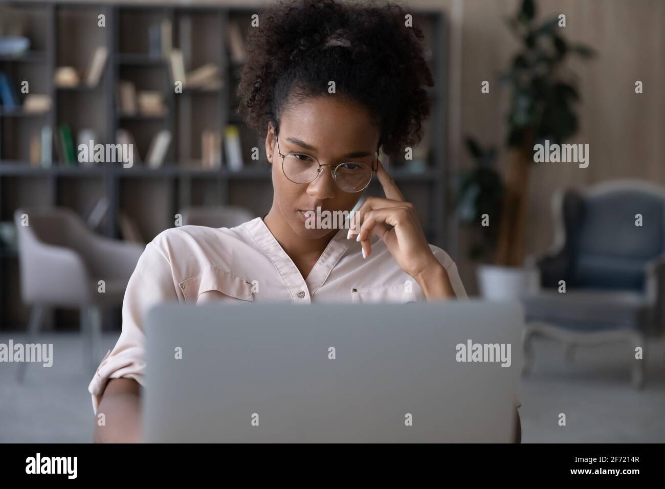 Nachdenkliche Birazialfrau arbeitet am Laptop-Denken Stockfoto