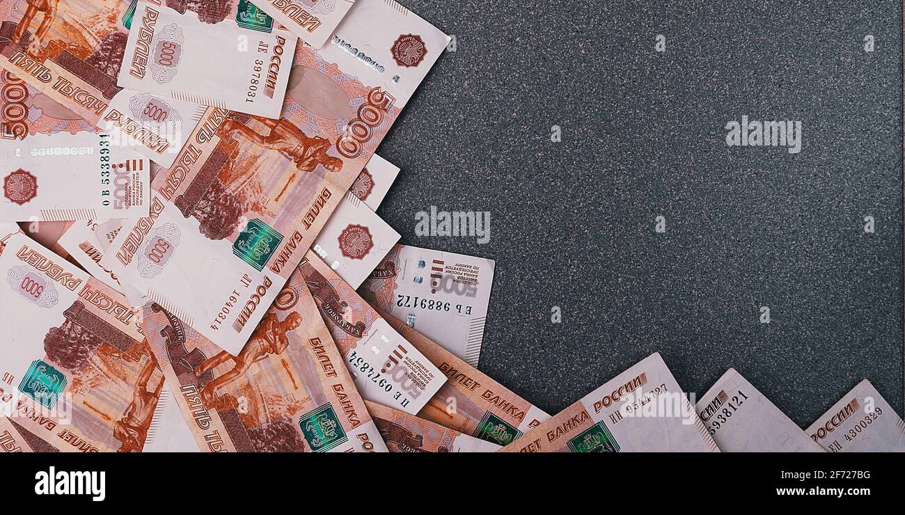 Russische Geldscheine von fünftausend Rubel, auf einem grauen Hintergrund verstreut, gibt es einen Platz für die Inschrift und den Text. Layout, Layout. Stockfoto