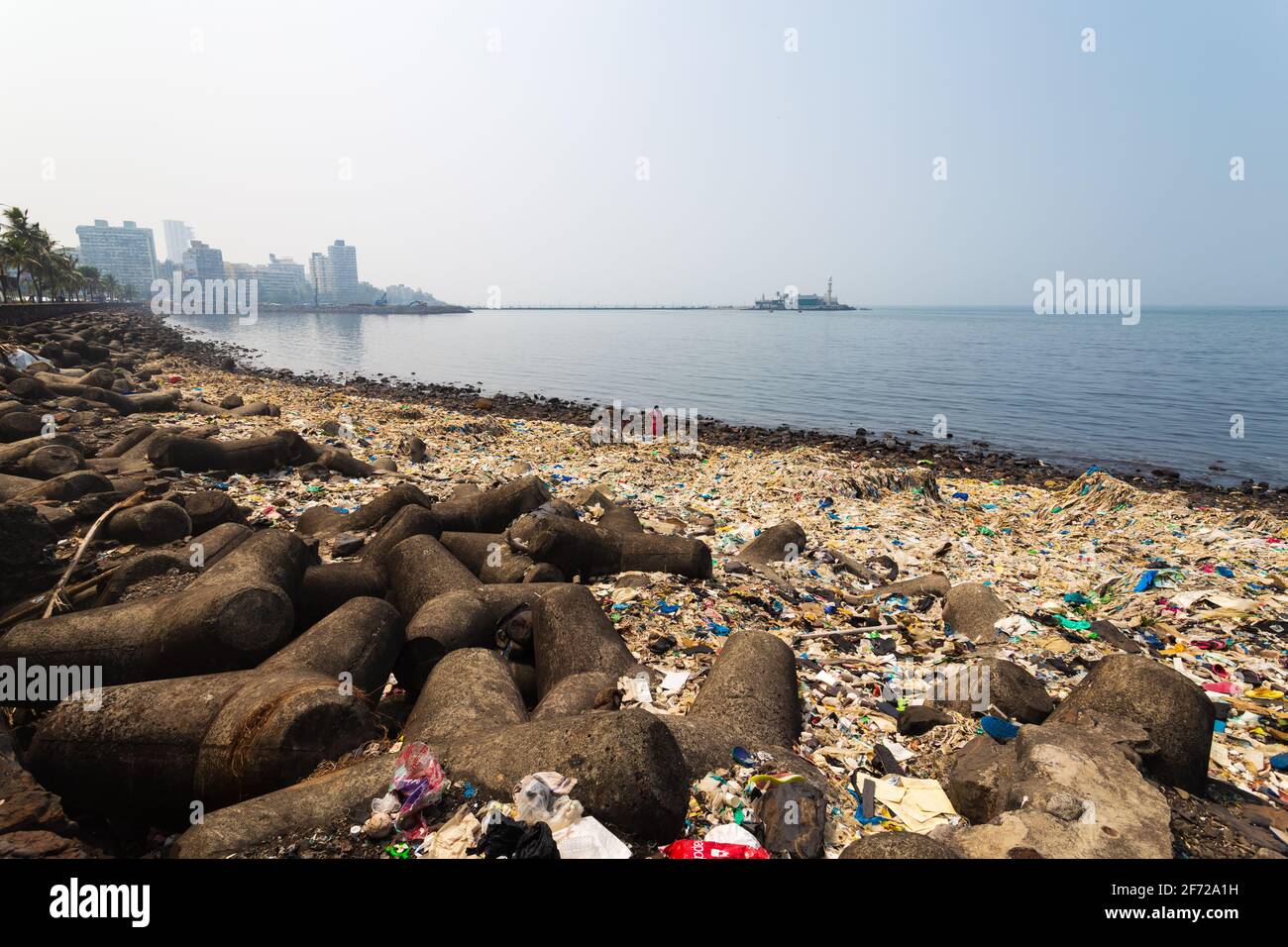 Die Küste von Mumbai ist mit einem Haufen Müll oder Plastik, modernen Stadtgebäuden und dem Hei Ali Dargah im Hintergrund gefüllt. Stockfoto