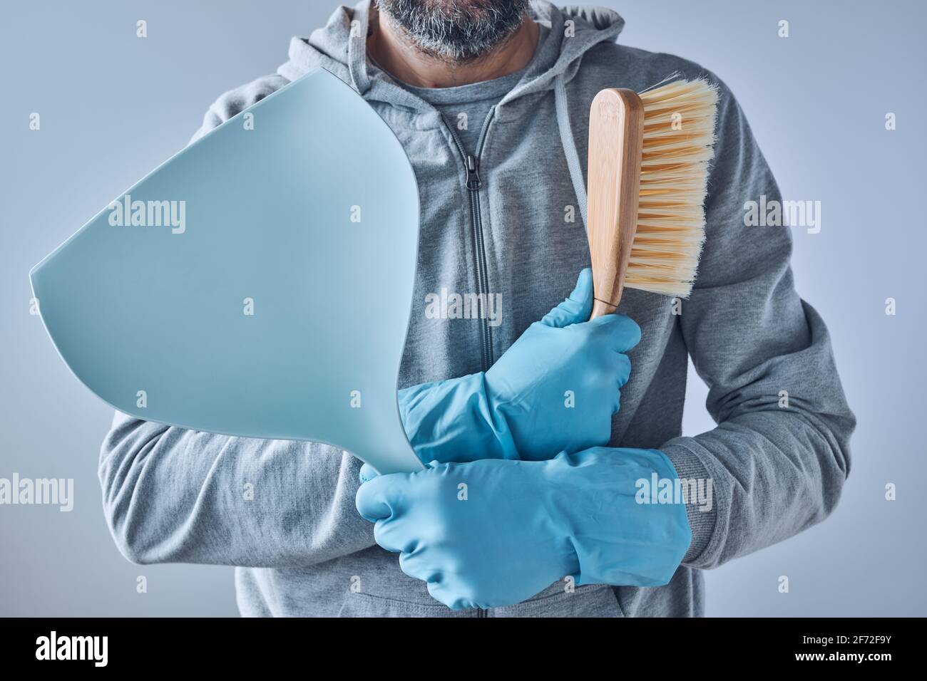 Bereit für die Hausreinigung, Mann mit Kehrschaufel- und Bürstenreinigungsausrüstung Stockfoto
