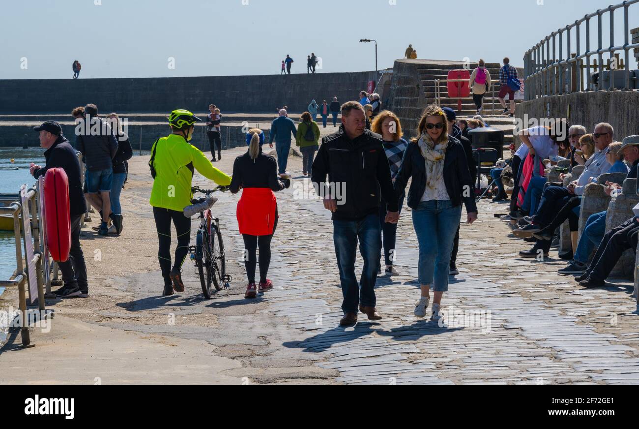 Lyme Regis, Dorset, Großbritannien. April 2021. Wetter in Großbritannien. An einem sonnigen Ostersonntag schlendern die Menschen entlang des Cobb Harbour. Kredit: Celia McMahon/Alamy Live Nachrichten Stockfoto