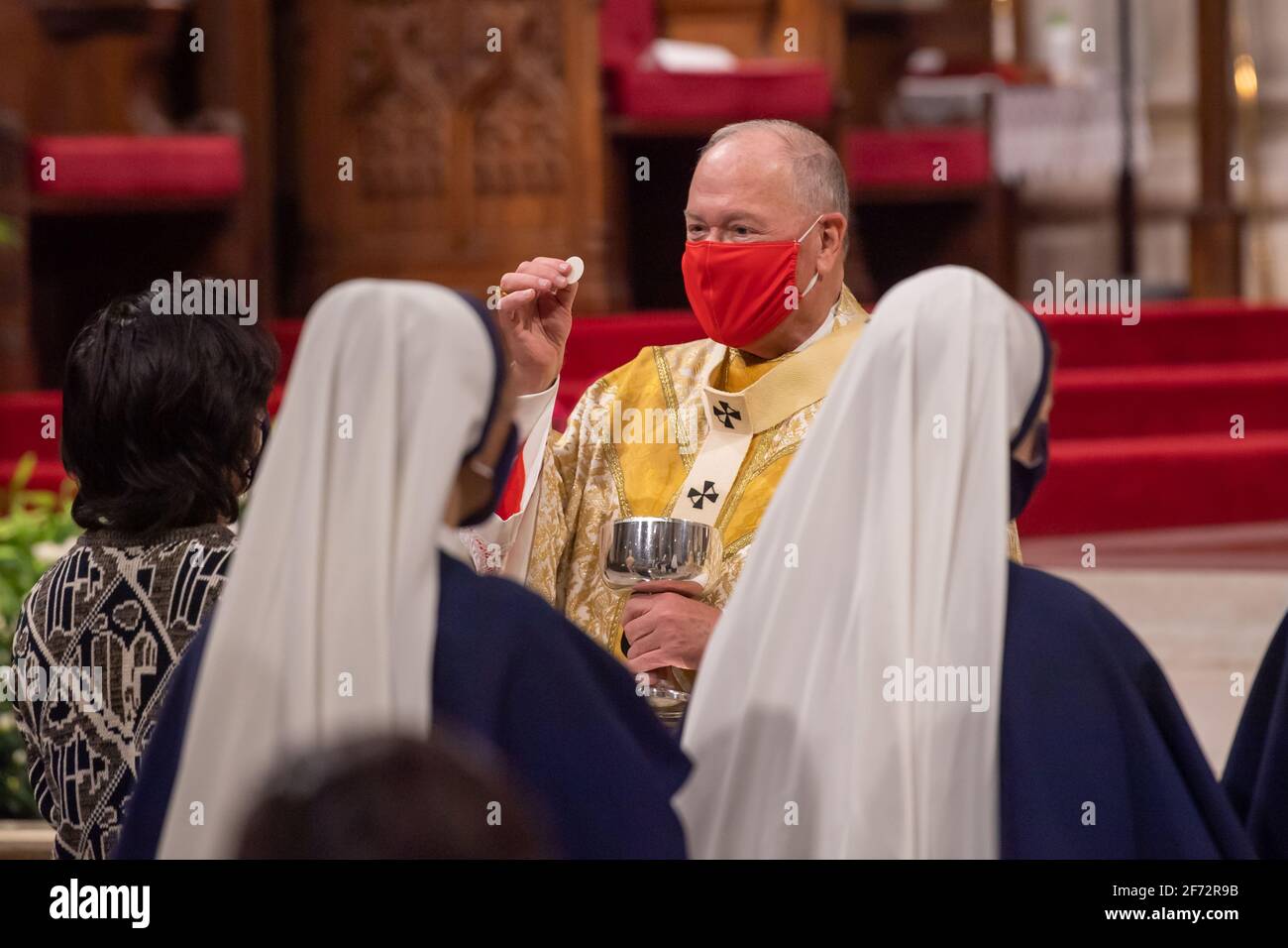 New York, Usa. April 2021. Gläubige empfangen die Heilige Kommunion während der Ostermesse in einer sozial distanzierten St. Patrick's Cathedral in New York City.der Gottesdienst, der aufgrund der anhaltenden Coronavirus-Pandemie in der Regel einer der größten des Jahres war, wurde von einer kleineren Menge und Geistlichen besucht. Die Messe wurde live im gesamten Tri-State-Gebiet übertragen. (Foto von Ron Adar/SOPA Images/Sipa USA) Quelle: SIPA USA/Alamy Live News Stockfoto