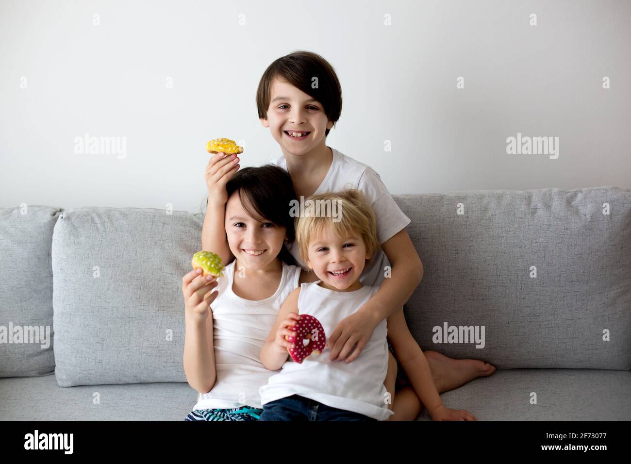 Drei Kinder, Knabensbrüder, Geschwister, essen zu Hause auf dem Sofa ...