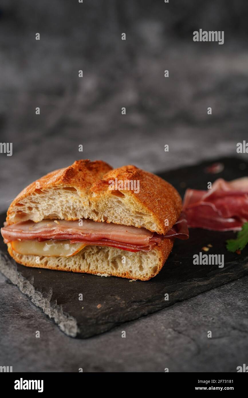 Einfaches Prosciutto Ciabatta-Sandwich in dunkel launischer Umgebung Stockfoto